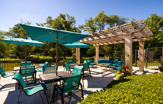 teal outdoor dining sets with umbrellas next to a pergola