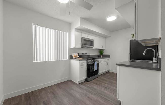 A modern kitchen with white cabinets and a wooden floor.