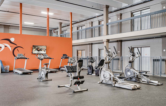 large fitness room with lots of equipment and orange wall