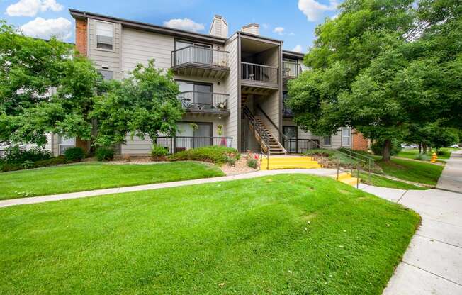 View of one of our apartment buildings with stairs and private patios and balconies at Greensview Apartments in Aurora, CO