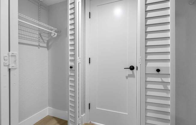 A white closet with a door and shelves.