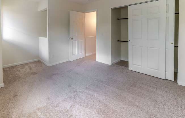 an empty bedroom with two closets and a carpeted floor