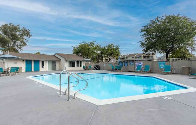 our resort style swimming pool is next to our apartments with a fence and trees