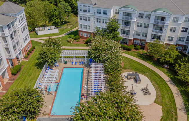 An aerial view of a pool surrounded by trees and buildings.