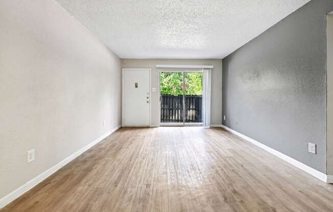A room with wooden floors and a white door leading to a balcony.
