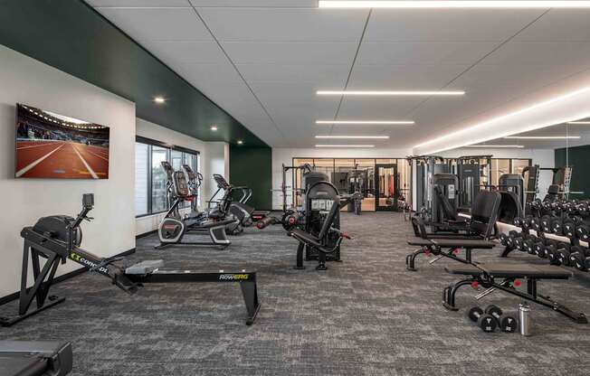 A gym with a variety of equipment including treadmills, weights, and exercise machines.