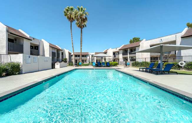 A long rectangular swimming pool in front of apartment buildings.