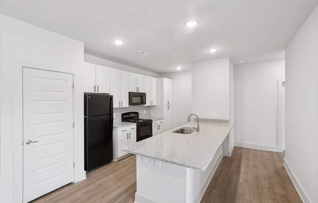 A kitchen with black appliances and white cabinets.