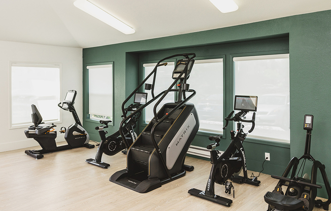 Brightly lit cardio area with stair climber and stationary bike options