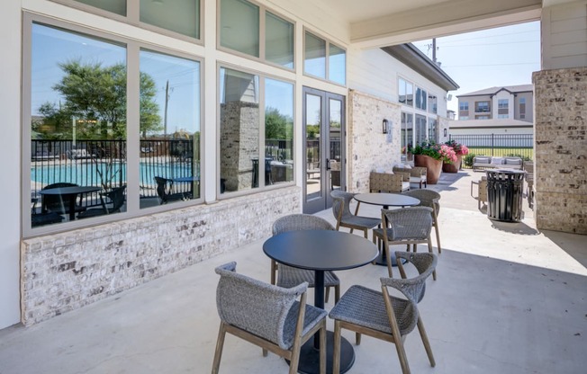 a patio with tables and chairs outside of a building with a pool