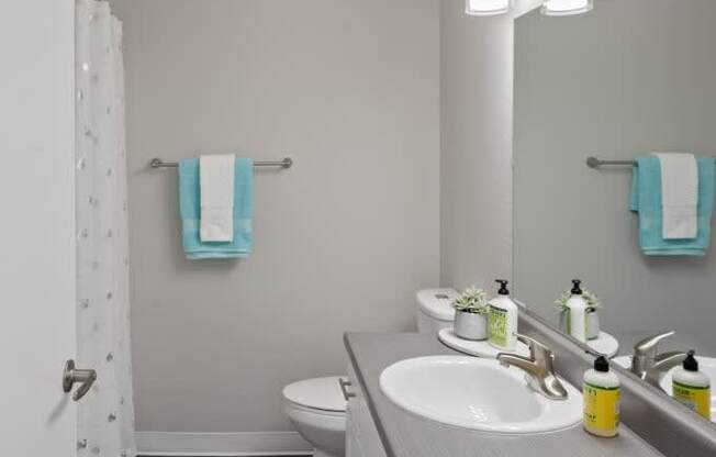 A bathroom with a white toilet, sink, and mirror.