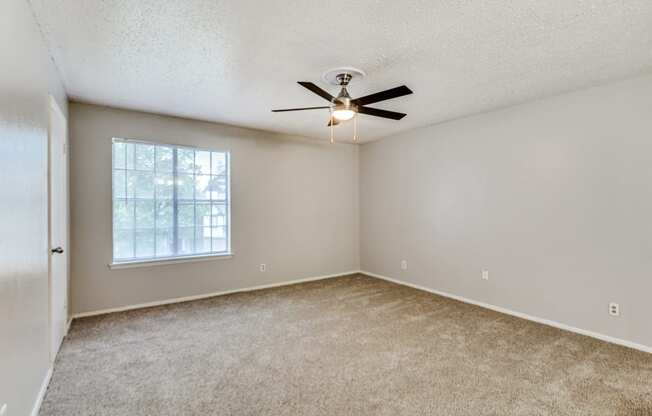 an empty living room with a ceiling fan and a window