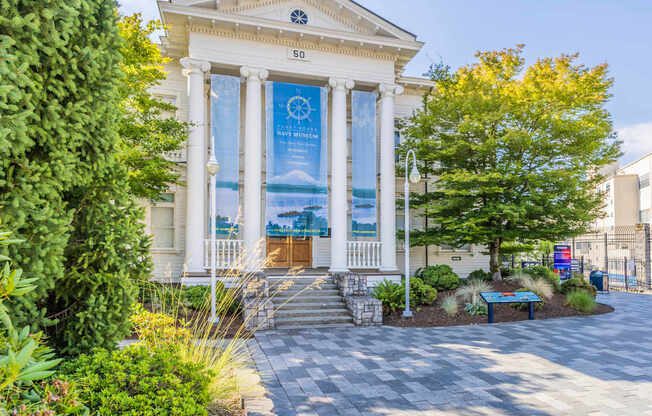 A white building with a banner on the front and a tree in front of it at Spyglass Hill Apartments, Bremerton, 98337