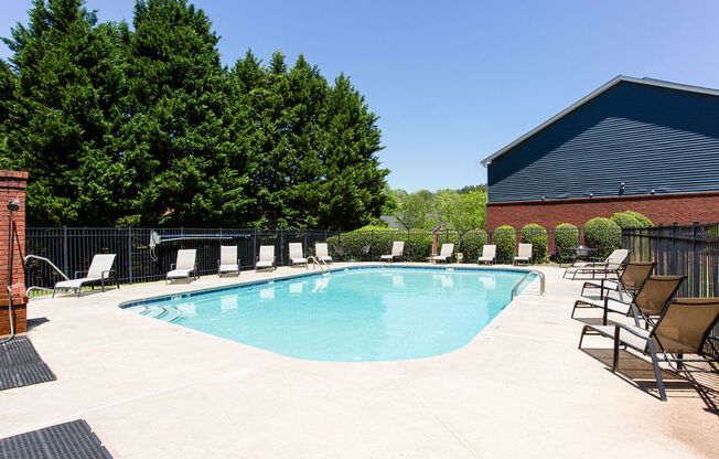 a swimming pool with lounge chairs and trees in the background