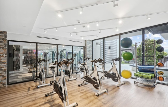 a gym with a variety of exercise equipment and large windows