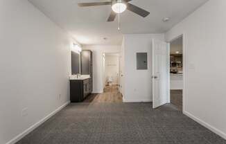 an empty living room with a ceiling fan and a kitchen