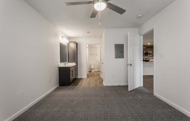 an empty living room with a ceiling fan and a kitchen