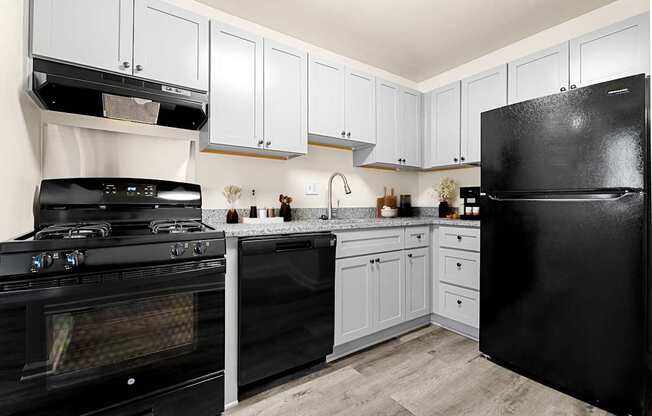 A black refrigerator sits in a kitchen with white cabinets.