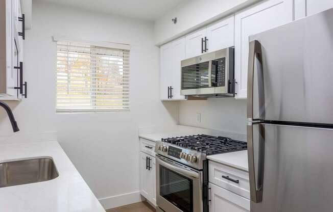 A kitchen with white cabinets and stainless steel appliances.