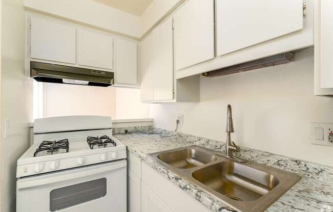 A white kitchen with a stove and sink.