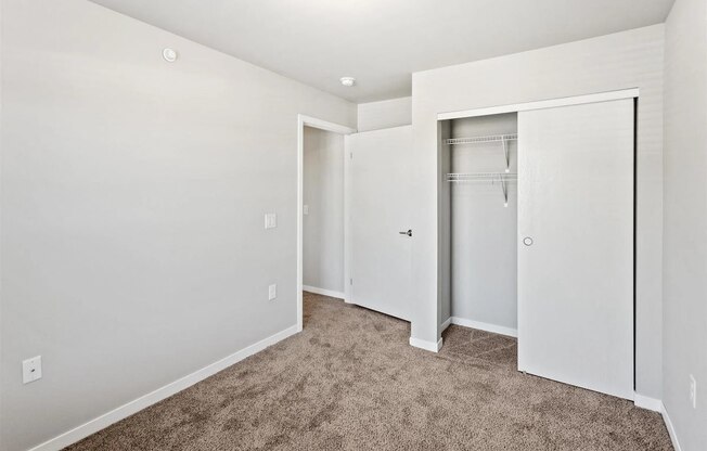 a bedroom with white walls, plush carpeting, and a closet at Muskego School