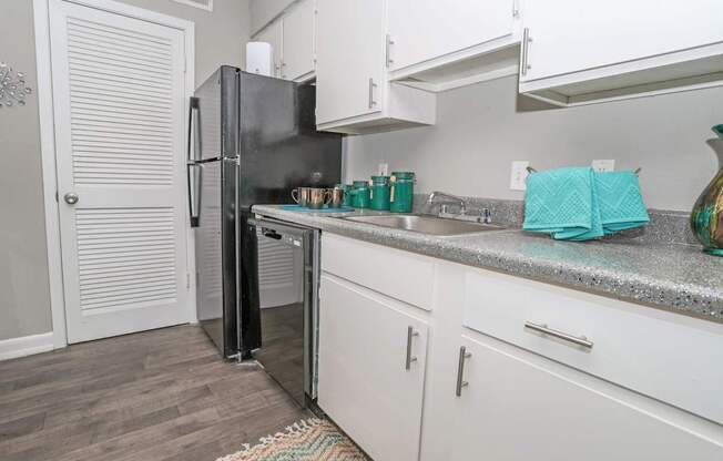 A black refrigerator is in a cypress kitchen with white cabinets at The Marq in Shreveport, LA