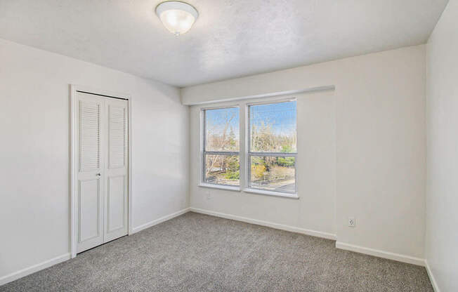 A bedroom with a large window and a walk-in closet at Black Sand Apartment Homes in Lincoln, NE