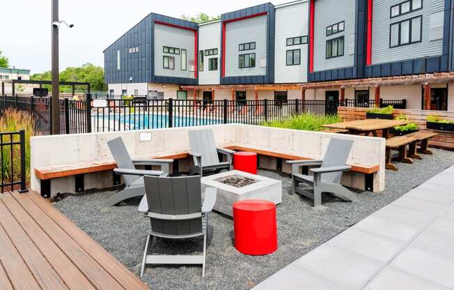 a seating area with tables and chairs in front of a row of buildings