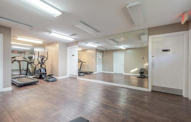 A spacious gym with treadmills, elliptical machines, and mirrors.