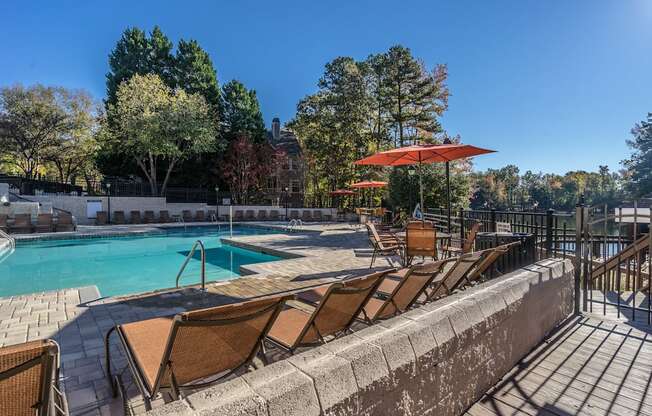 a swimming pool with chairs and umbrellas on a sunny day at Radbourne Lake Apartments, Charlotte, NC 28269 ? 