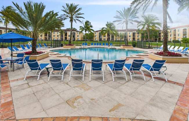 A pool surrounded by chairs and palm trees.