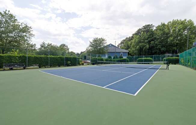 a blue and green tennis court with a bench