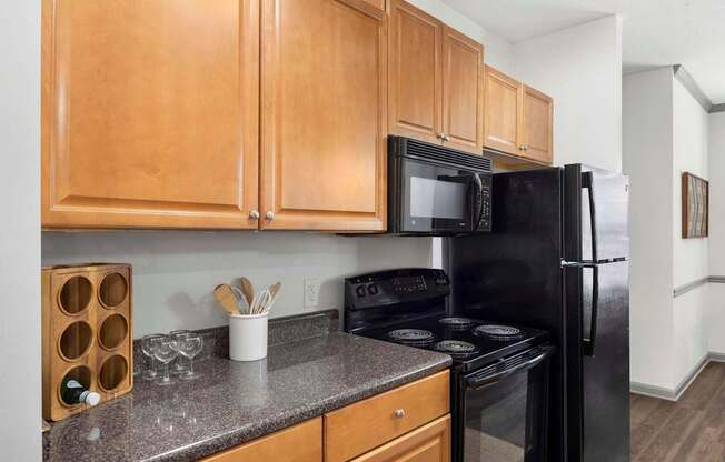 A kitchen with black appliances and wooden cabinets.