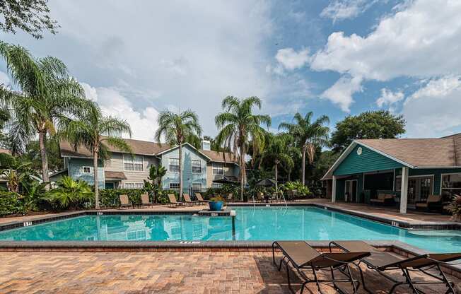 a swimming pool with chairs and houses in the background