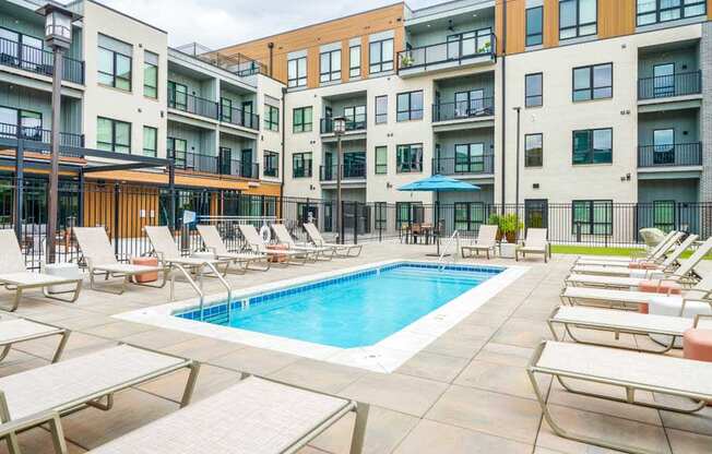 A lounge pool surrounded by several lounge chairs and umbrellas for shade.