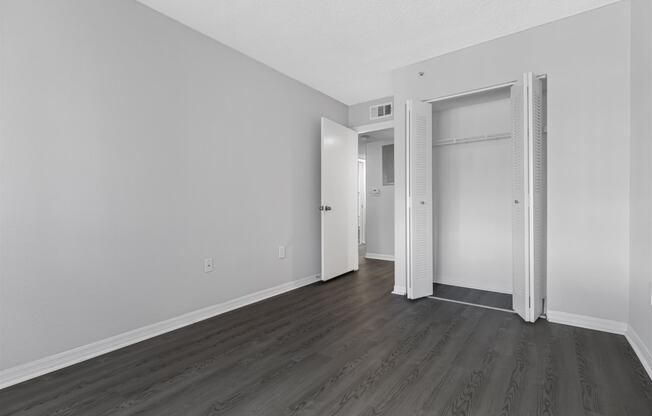 an empty room with white walls and wood flooring and a closet