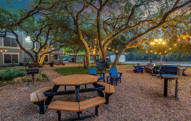 A picnic area with tables and chairs under trees.