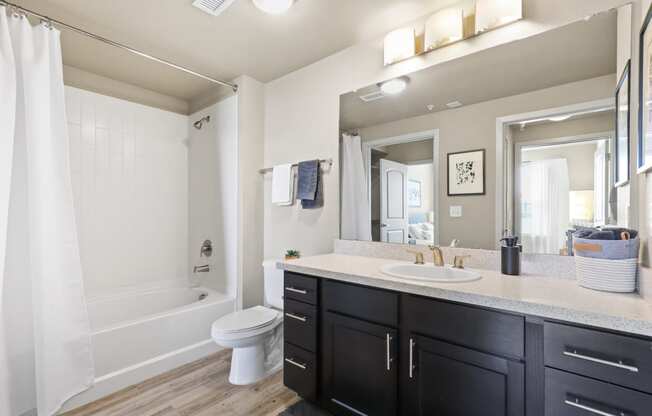 a bathroom with a large mirror and a sink and a toilet at Ridge at Thornton Station Apartments, Colorado