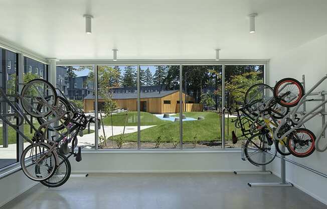 a room with bikes hanging on the wall and a large window with a view of a yard