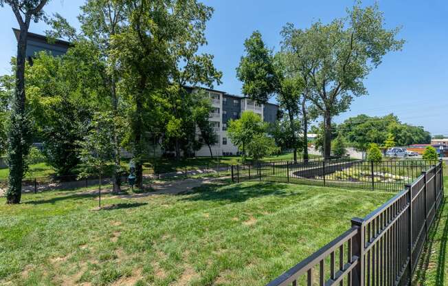 a grassy area with trees and a fence in front of a building