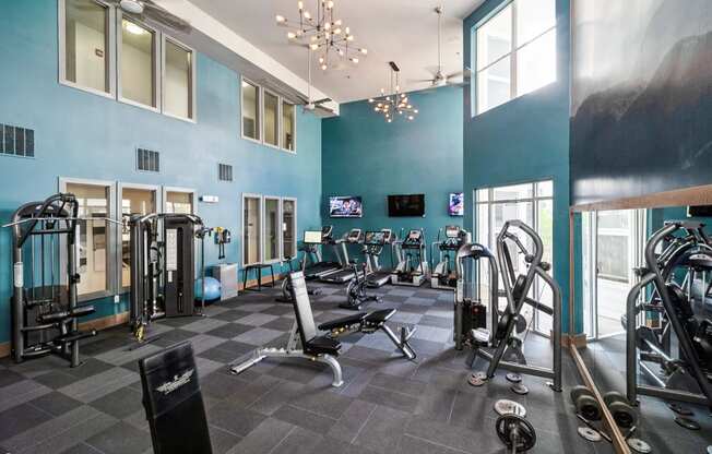 A gym with a variety of equipment including treadmills, weights, and exercise machines.