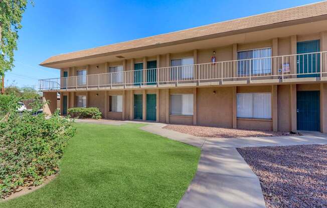 A sunny day at the apartment complex with green grass and bushes.