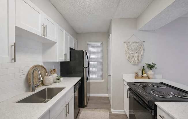 A kitchen with black appliances and white cabinets.