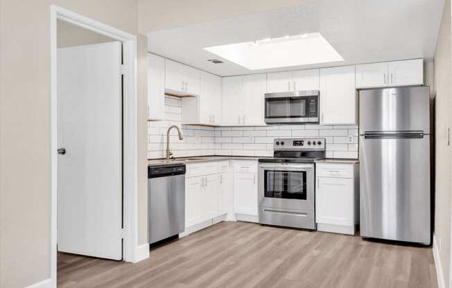 a kitchen with white cabinets and stainless steel appliances