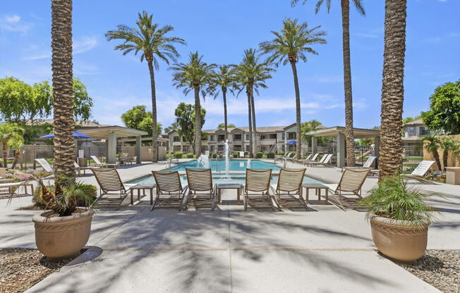 a swimming pool with chaise lounge chairs and palm trees at Adiamo Palm Valley, Goodyear, AZ