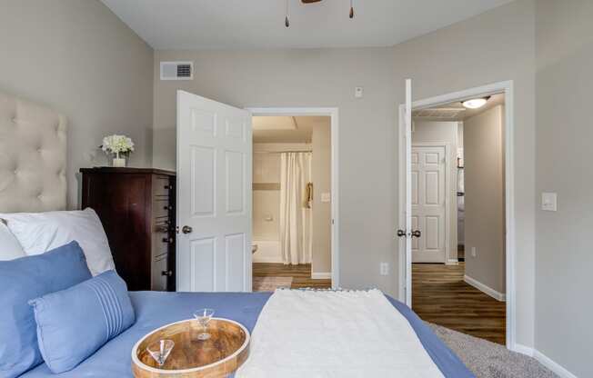 a bedroom with a bed and a dresser and a hallway with a door open