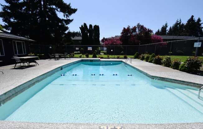 the pool is surrounded by a fence and some trees