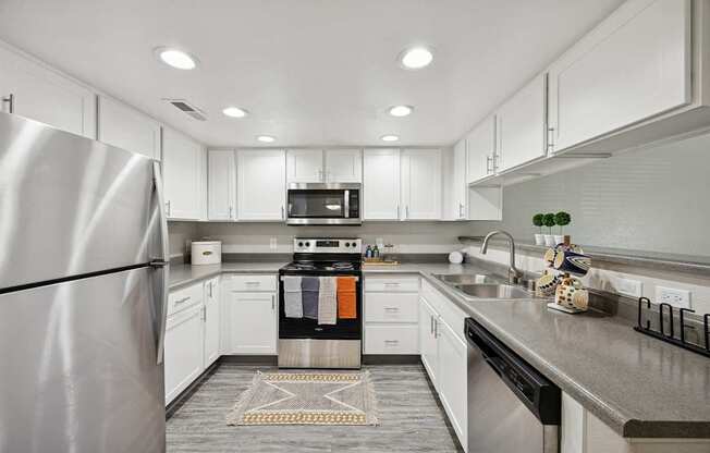 A modern kitchen with a stainless steel refrigerator and white cabinets.