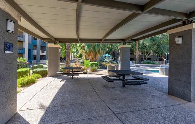 A concrete patio with a table and chairs under a roof.