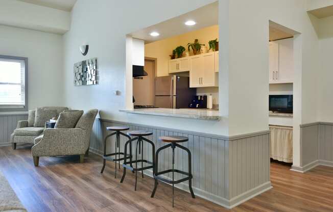 a kitchen and living room with a bar and stools at Heatherwood Apartments, Grand Blanc